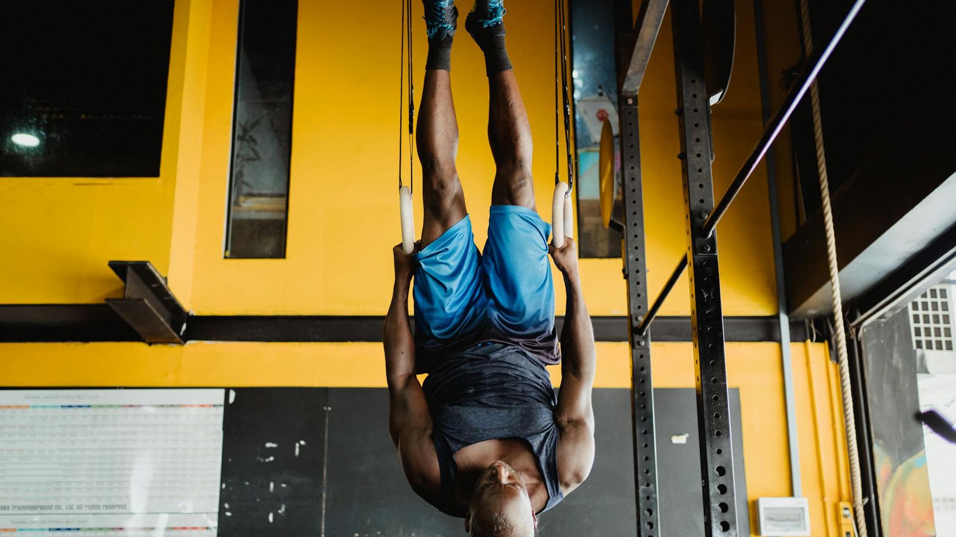 Man performing a controlled strength exercise in a dark, minimalist gym.